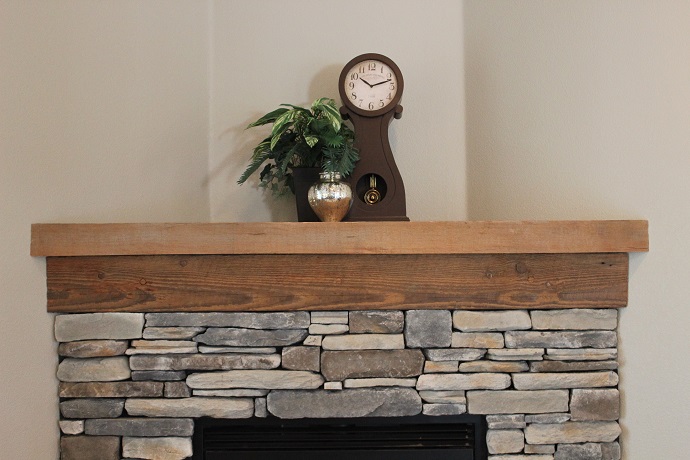 reclaimed wood fireplace mantel with clock and plant